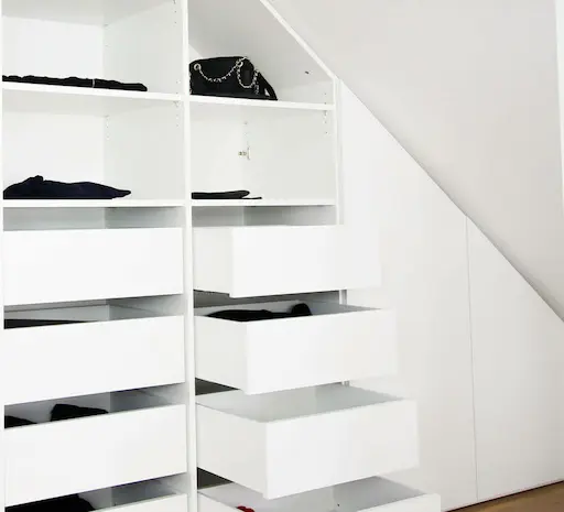 Detail-Aufnahme von innenliegenden Schubladen in einem offenen weissen Dachschrägenschrank
