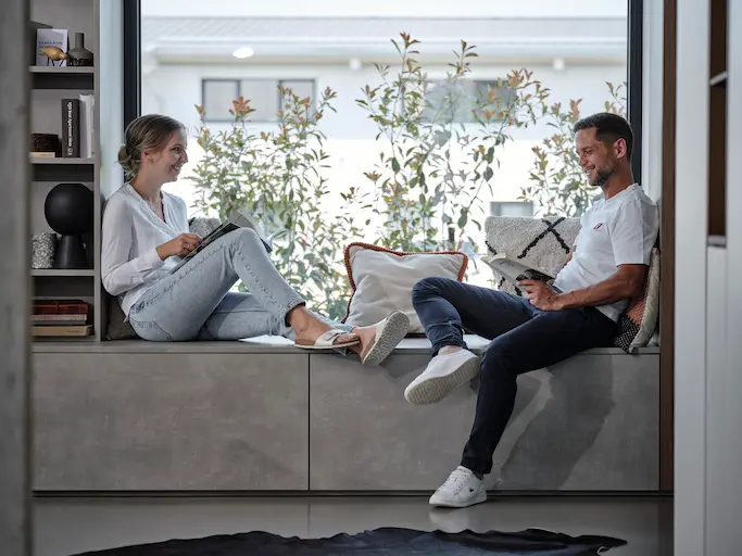 Eine Frau und ein Mann sitzen auf einem Sideboard und lesen.