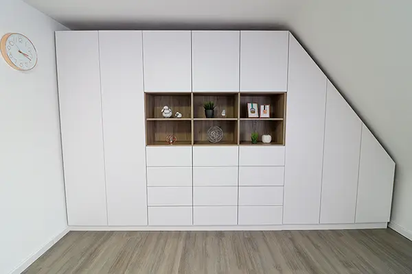 Dachschraegenschrank im Wohnzimmer, Holz mit weissen Fronten und Dekoration.