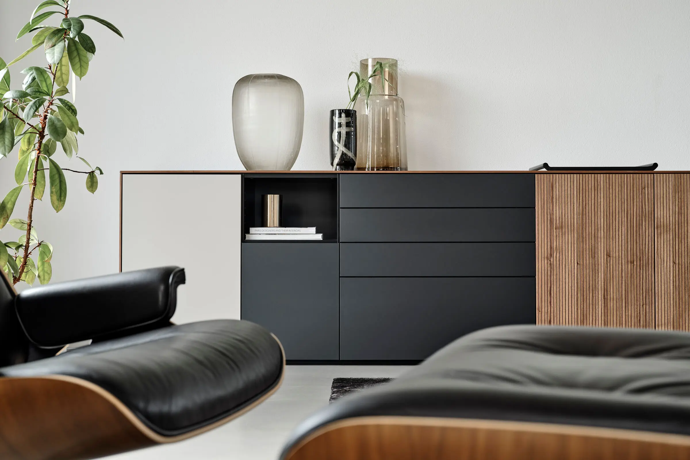 Sideboard in Schwarz mit verschiedenen Fronten und Dekoration.