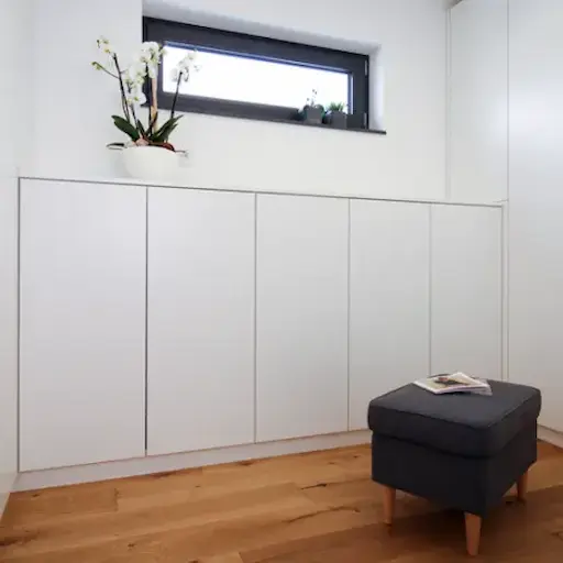 Sideboard Einbauschrank in Weiss mit Hocker und Pflanze.