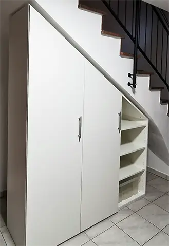 Schrank mit Schraege unter der Treppe in Weiss.