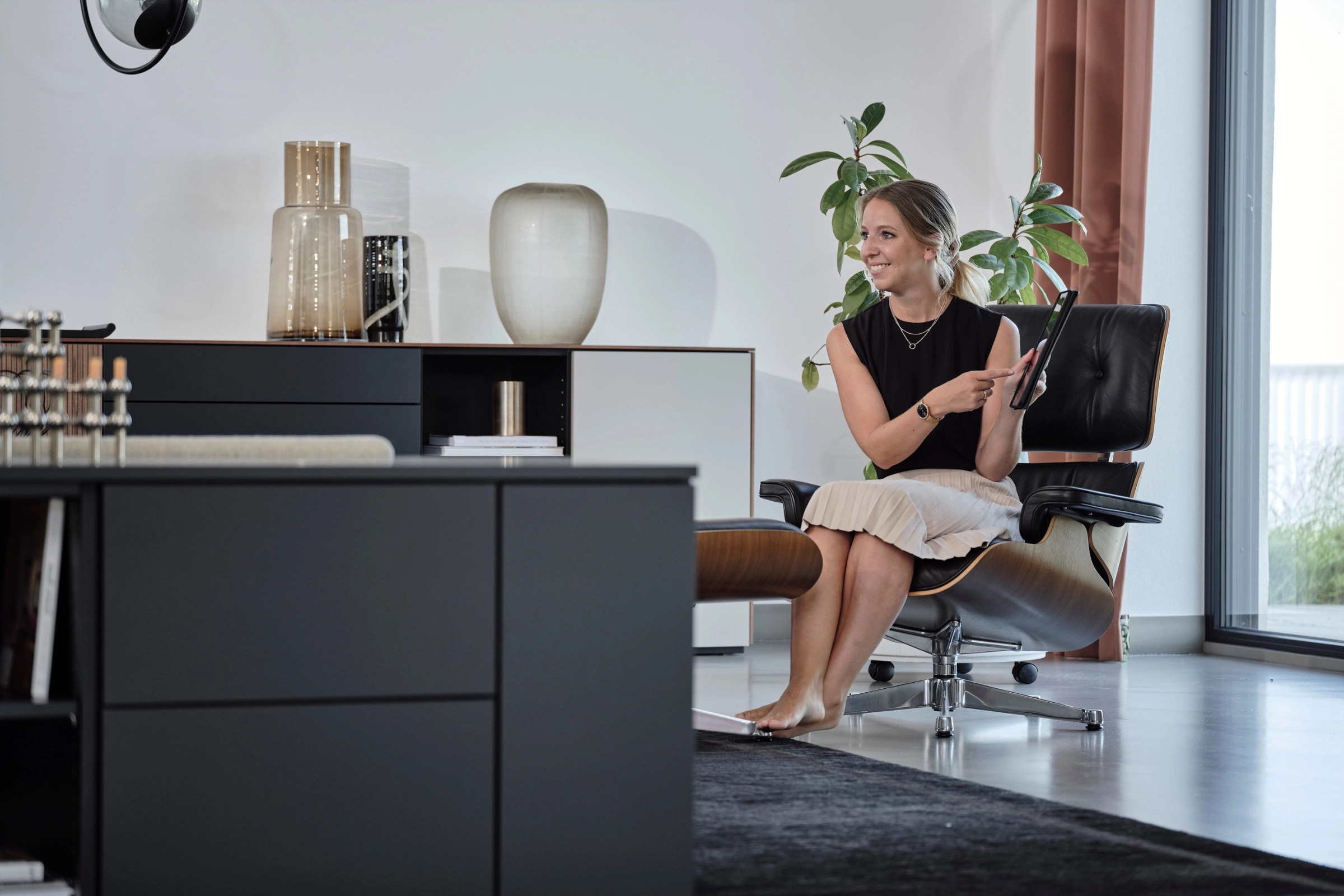 Sideboard in Schwarz mit Frau im Hintergrund.